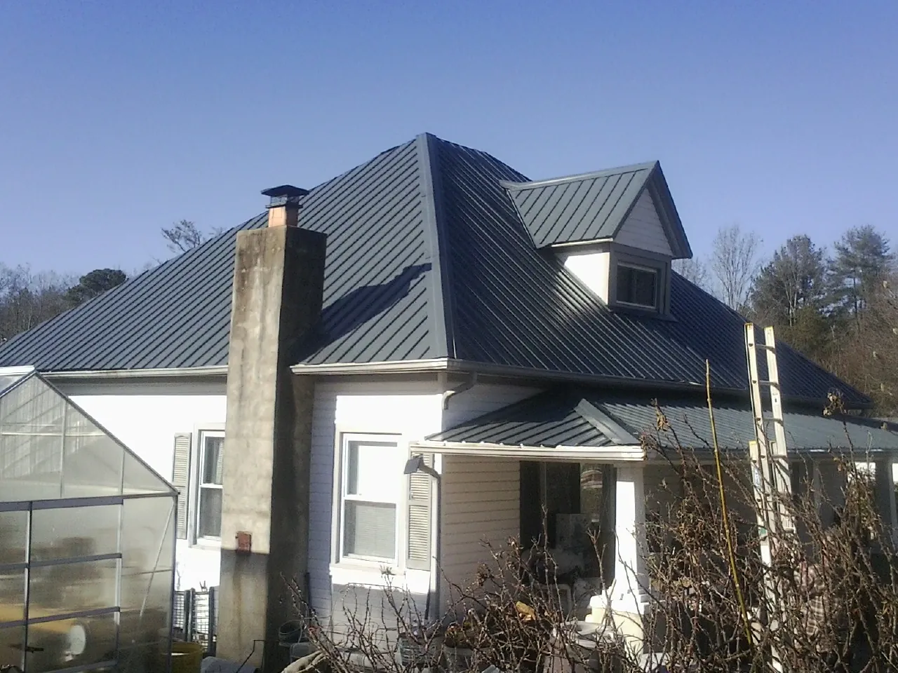 Dark blue standing seam metal roof on a white farmhouse with dormer — Slate & Tile Roof Repair by Roofing Brothers in Granite Quarry