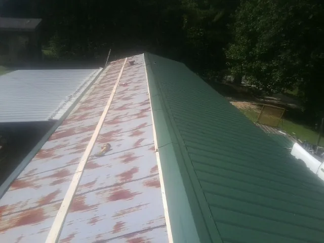 Old rusted panels beside newly installed green metal roofing — Wind Damage Roof Repair by Roofing Brothers in Granite Quarry