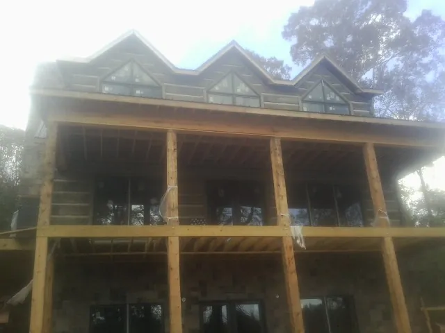 Dormers and porch framing on a large log home under construction — Roof Coating work by our crew in Granite Quarry