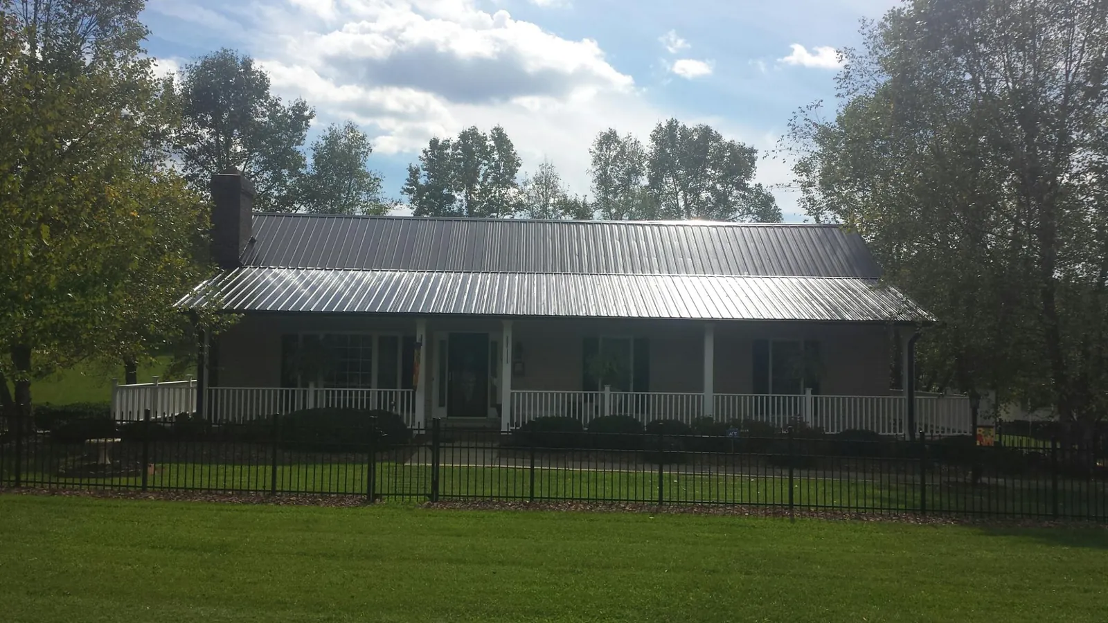 Gray metal roof on a brick ranch with a full width front porch — Gutter Guard Installation work by our crew in Granite Quarry