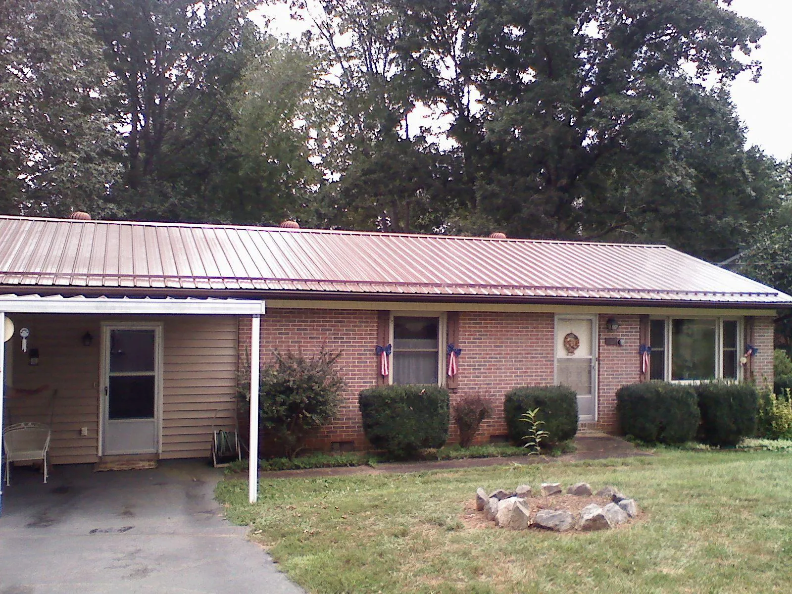 Bronze metal roof and carport on a brick ranch home — Roof Repair work by our crew in Granite Quarry