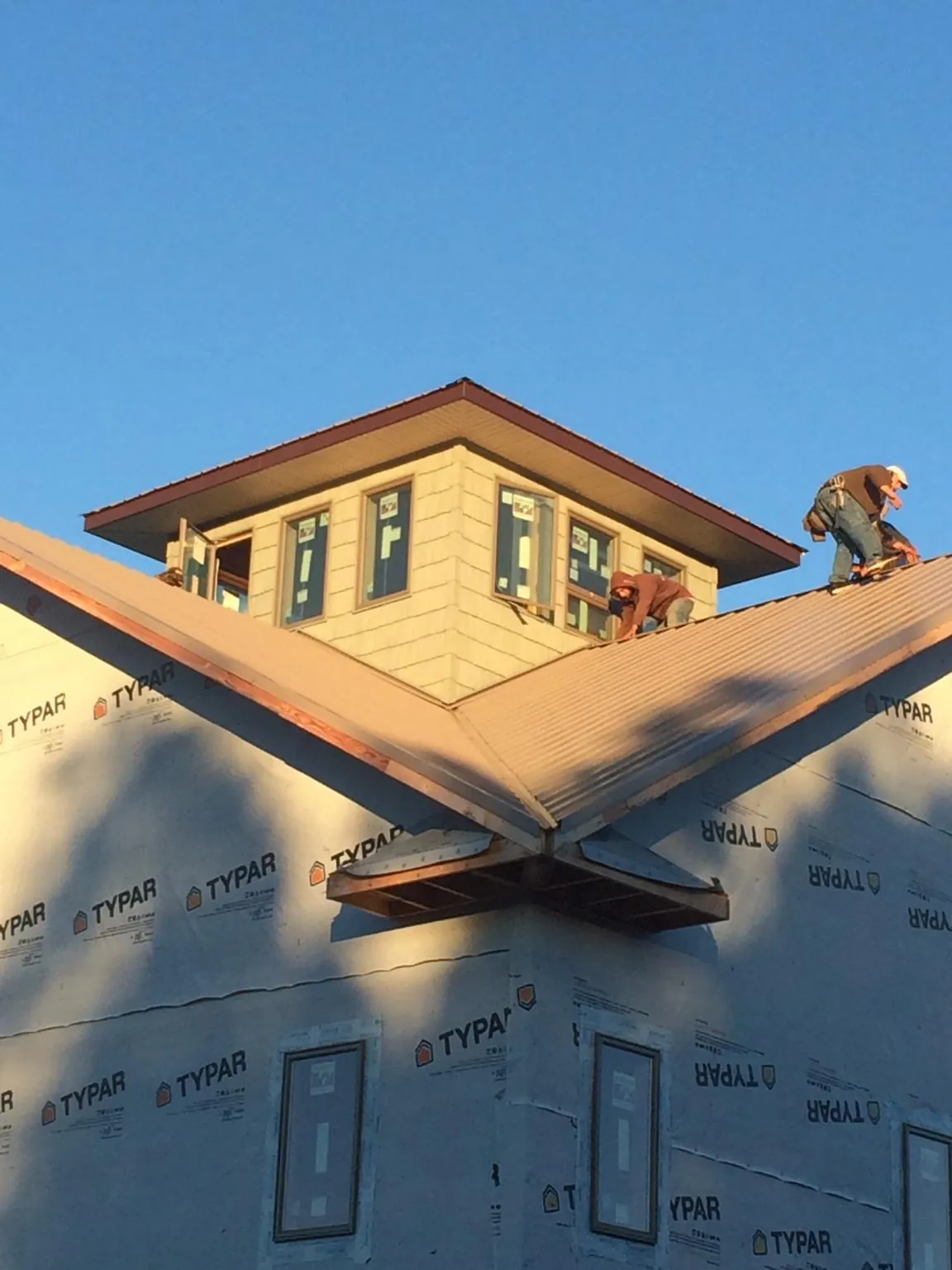 Roofers working around a rooftop cupola on a new metal roof at sunset — Roof Waterproofing in Granite Quarry by Roofing Brothers